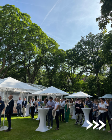 Mehrere Personen an Stehtischen beim Sommerfest
