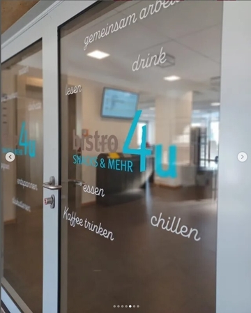 Tür zur Mensa. Auf den Scheiben der Tür sind verschiedene Aufkleber geklebt mit "drink", "lesen", "chillen", "essen", "Kaffee trinken" usw.