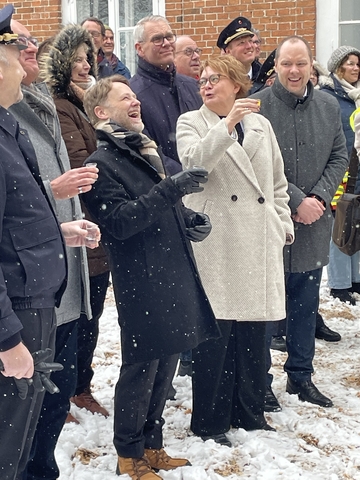 Finanzminister Heere, Innenministerin Behrends und weitere Zuschauer lachend im Schnee. Teilweise gucken die Teilnehmer nach oben.