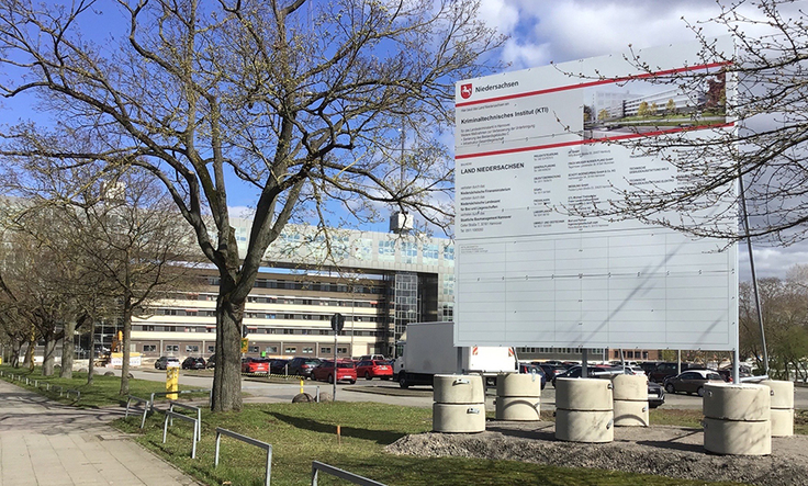 Bauschild vor dem Bestandsgebäude