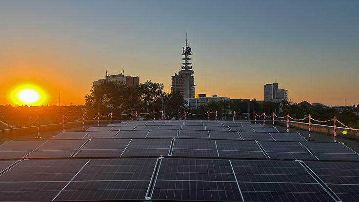 Photovoltaik-Anlage auf Dach bei Sonnenaufgang.