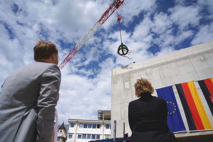 Finanzminister Heere und Innenministerin Behrens beobachten, wie der Richtkranz aufs Gebäude gehoben wird.