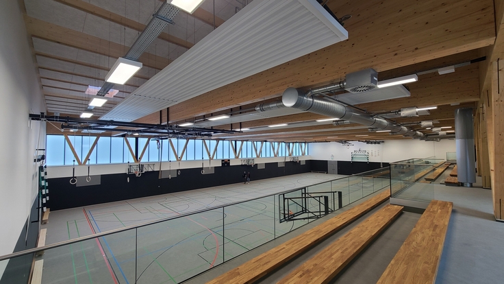 Blick von der Zuschauertribüne in eine großzügige Sporthalle mit vielen Holzelementen