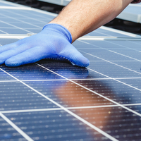 Hände mit Schutzhandschuhen in Nahaufnahme, die ein PV-Modul platzieren