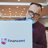 Kritischer Blick eines Bürgers auf ein Notebook mit der Aufschrift Finanzamt